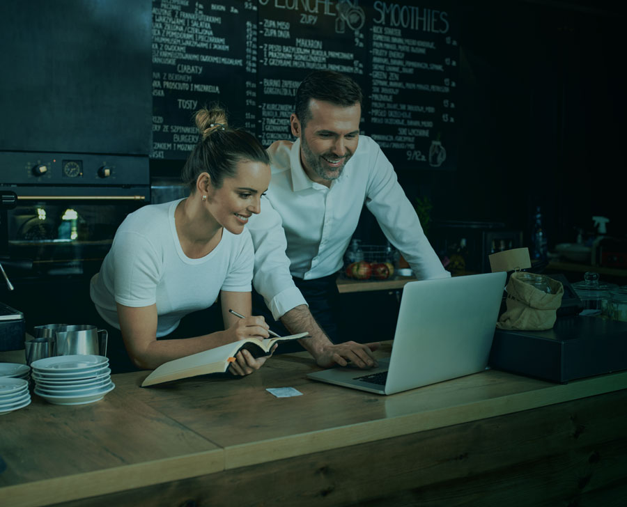 Nainen ja mies katsomassa tietokonetta yhdessä kahvilassa