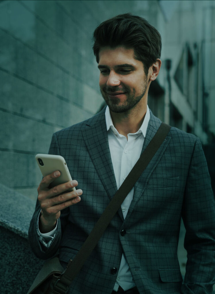 en man tittar på sin telefon medan han står i sanden